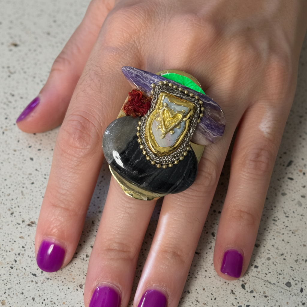 Close-up of a hand wearing a colorful ring with purple nail polish on a white fur background
