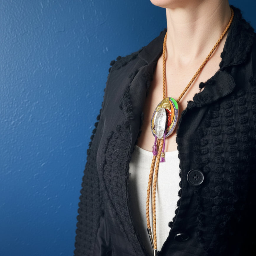 Mannequin wearing a black textured garment with a colorful necklace.