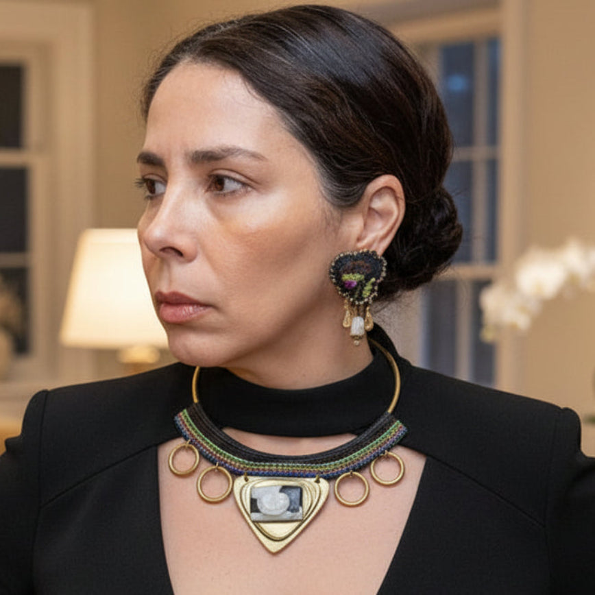 Woman in a black outfit with a detailed necklace in an elegant room.