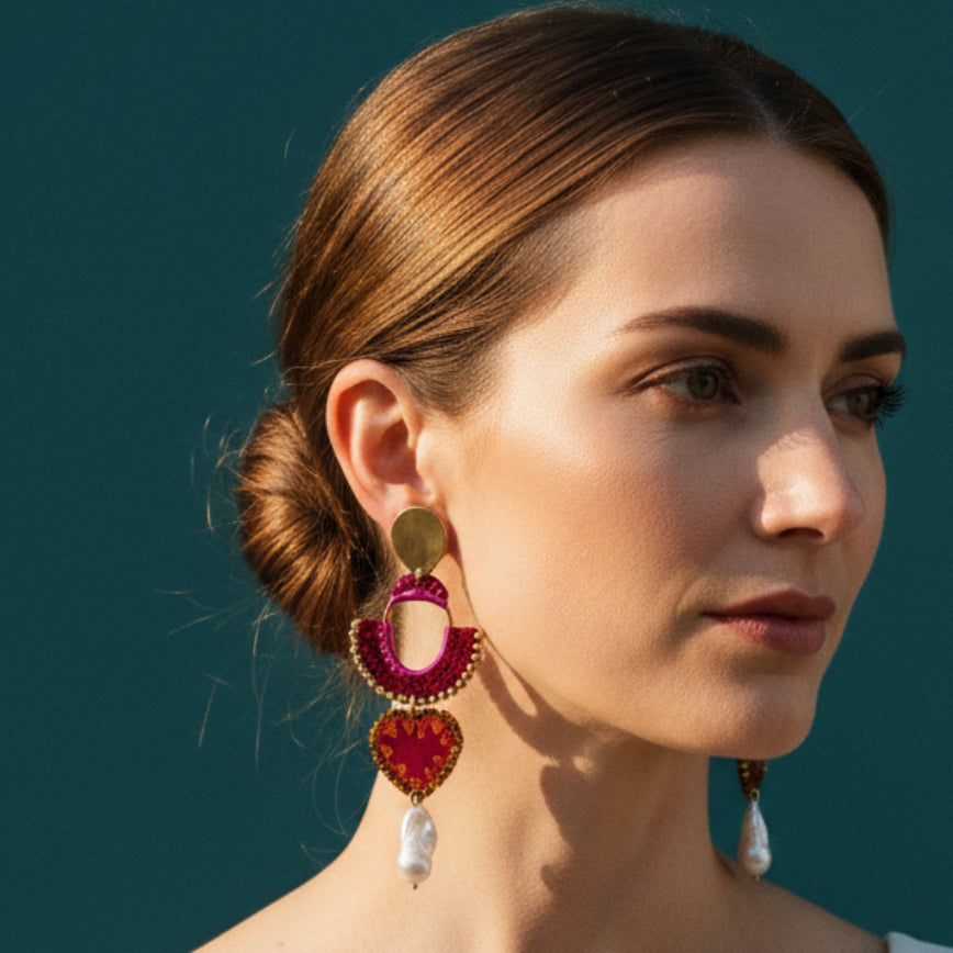 Decorative earring with pink and gold design on a light fabric background