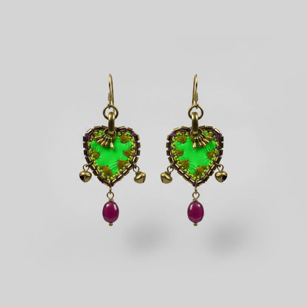 Pair of earrings with green and purple stones on a gray fabric background