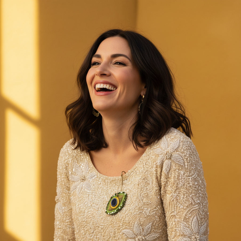 A close-up of a beige beaded blouse displayed on a white dress form mannequin. The blouse features intricate floral beadwork, a scoop neckline, and a decorative sunflower brooch pinned near the neckline.