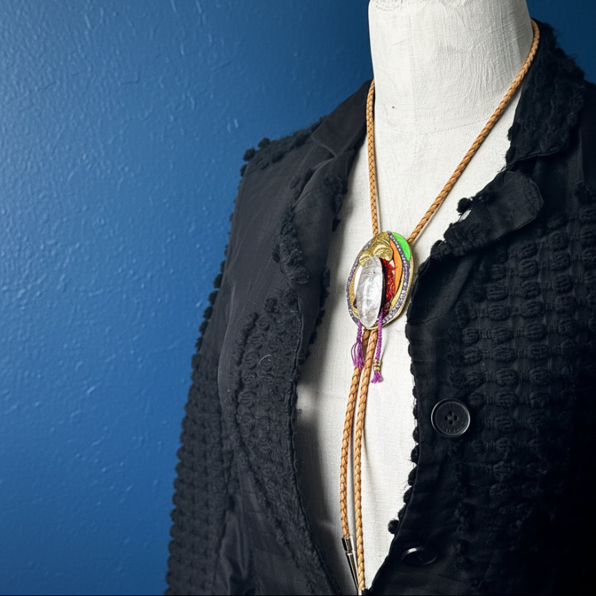 Mannequin wearing a black textured garment with a colorful necklace.