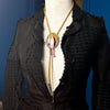 Black textured jacket on a mannequin with a colorful necklace against a neutral background