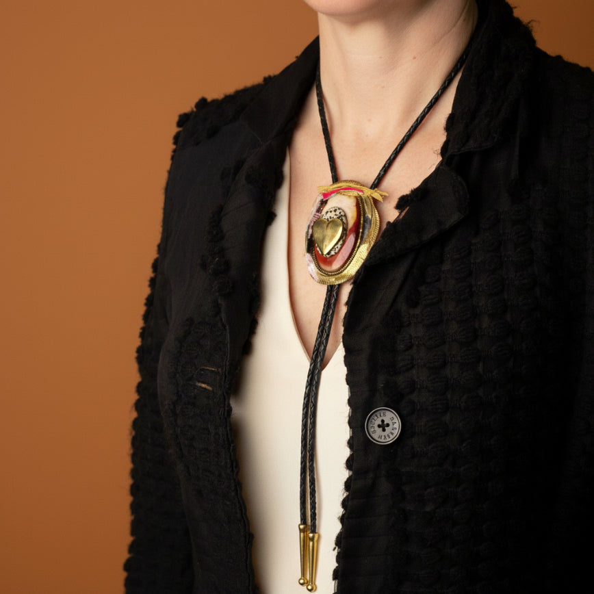 Mannequin wearing a black garment with a decorative necklace featuring a heart-shaped pendant.