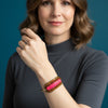 Colorful beaded bracelet on a clear stand against a gray background