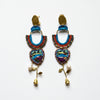 Colorful beaded earrings with heart designs and pearl-like beads on a textured fabric background