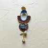 Colorful macrame earring with floral design on a textured white background