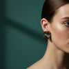 Pair of heart-shaped earrings with colorful beads on a textured fabric background