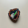 Colorful beaded brooch on a textured gray background