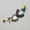 Colorful macrame hoop earring with decorative elements on a textured fabric background