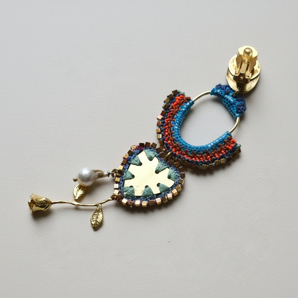 Colorful macrame hoop earring with decorative elements on a textured fabric background