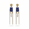 Pair of earrings with blue fabric, chains, and pearls on a textured gray background