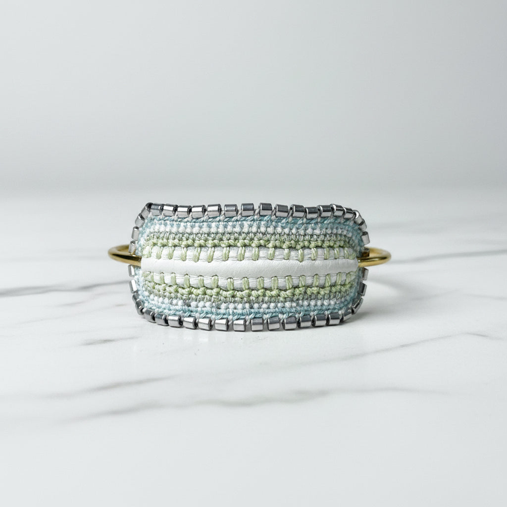 Beaded cuff bracelet with gold accents on a light gray surface