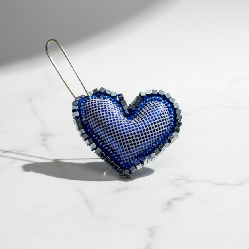Heart-shaped blue and silver decorative item on a textured gray background