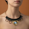 Necklace with multicolored beads and a heart-shaped pendant worn by a person on a gray background