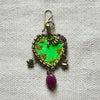 Decorative keychain with green and gold design on a textured white background