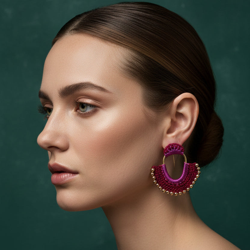 Pair of pink and gold earrings on a textured metal surface