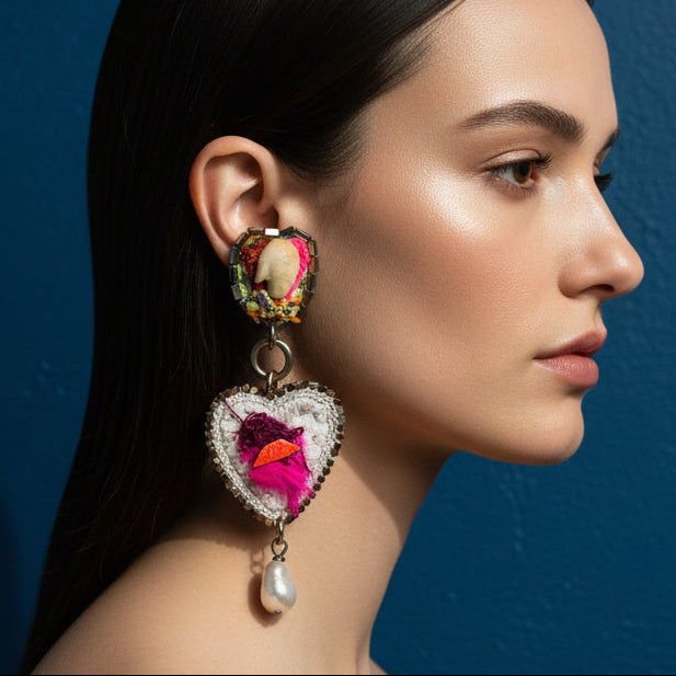 Heart-shaped earrings with colorful designs on a textured fabric background