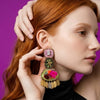 Woman wearing colorful earrings against a purple background