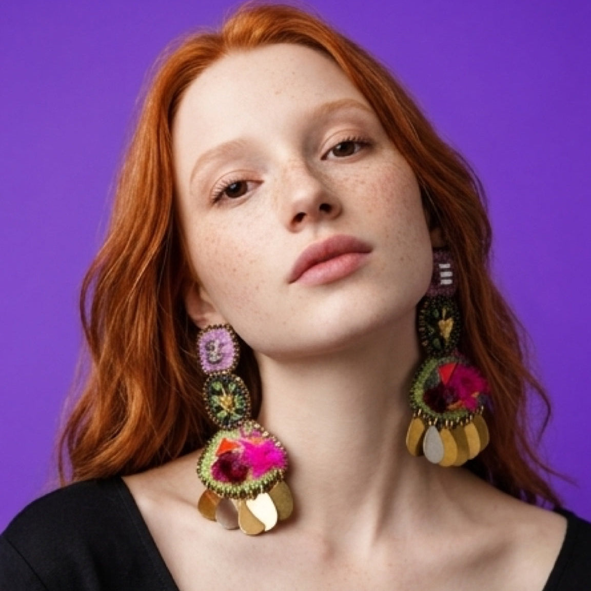 Woman wearing colorful earrings against a purple background