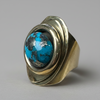 Ring with turquoise stone and gold band on a white background