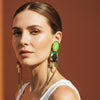 Pair of decorative earrings with green gemstones and chain designs on a light gray background
