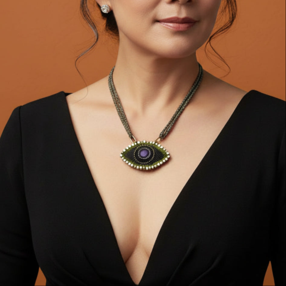 Woman wearing a black dress with a deep neckline and an eye-shaped pendant necklace.