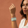 Multistrand beaded bracelet with gold clasp on a textured fabric background