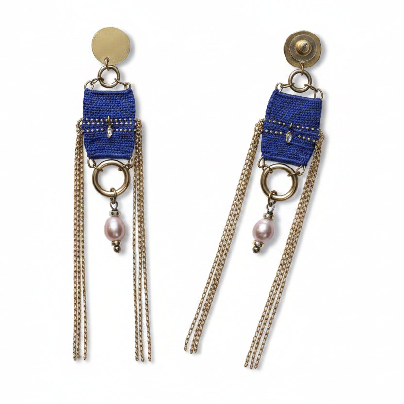 Pair of blue beaded earrings with chains on a textured gray background