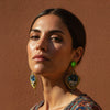 Woman wearing colorful earrings against a brown background