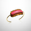 Beaded bracelet with pink and gold accents on a gray background