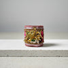 A handmade cuff bracelet made from pink and purple textured fabric, decorated with gold-tone metal key charms, a gold heart pendant, and a bright pink ruffled accent, resting on a white surface.