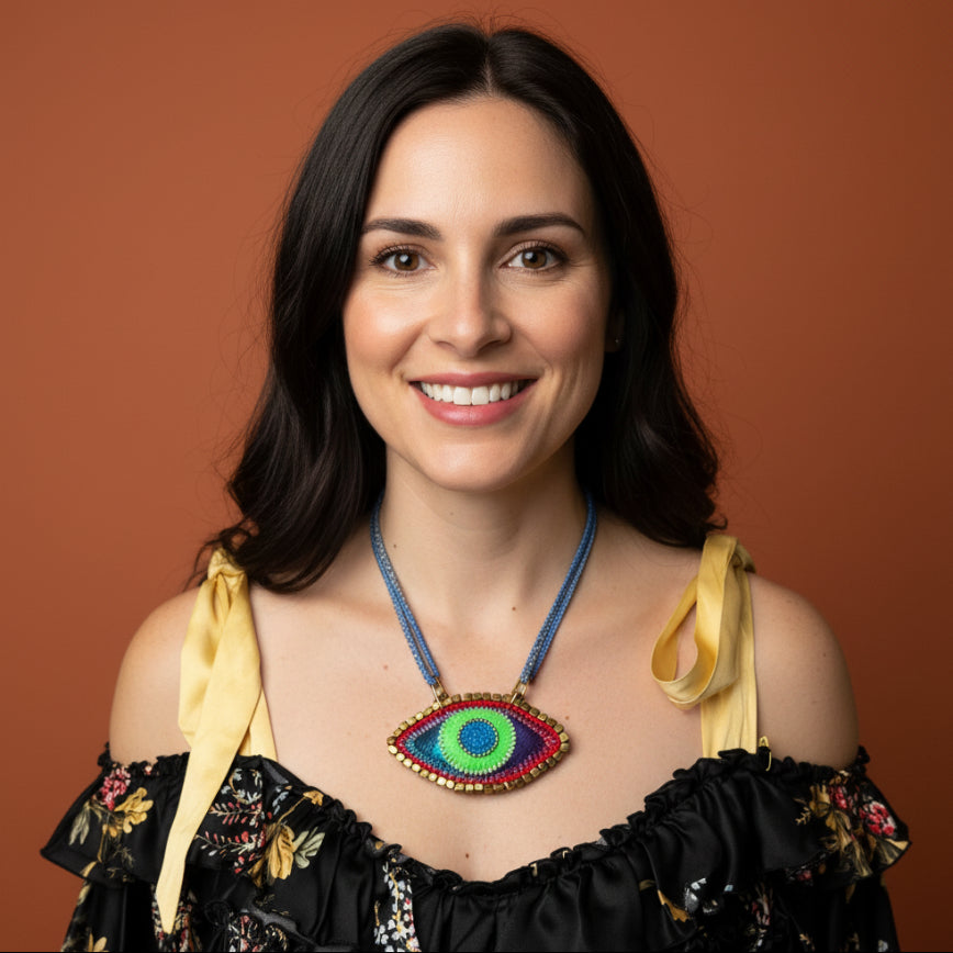 Mannequin wearing a black floral dress with yellow accents and a colorful necklace against a gray wall.